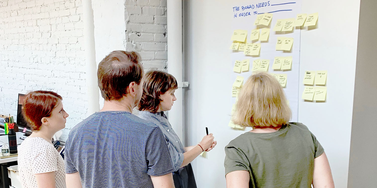 Four people in front of a board of post-its, brainstorming