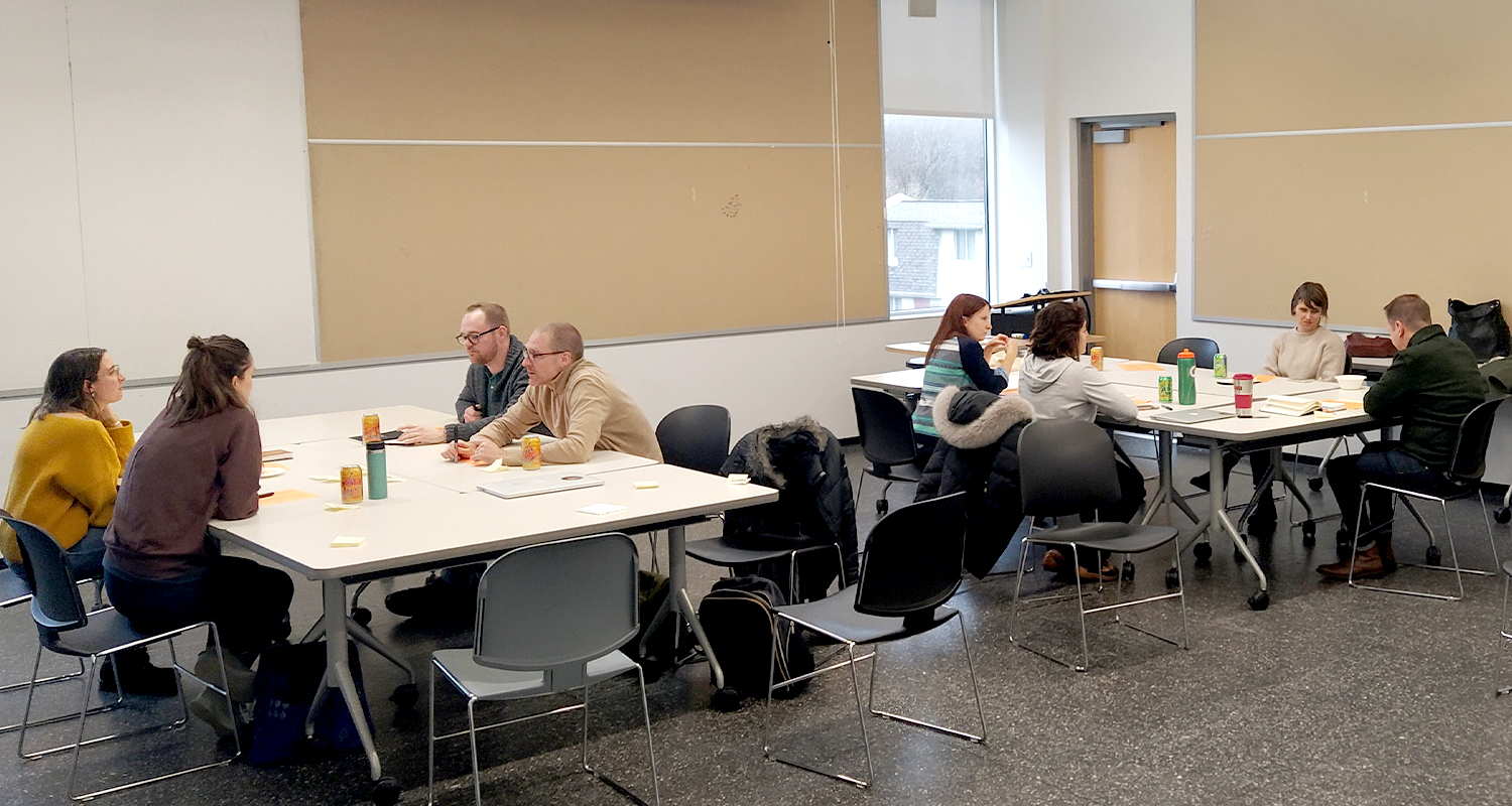 Eight people sitting around two tables in two groups of four