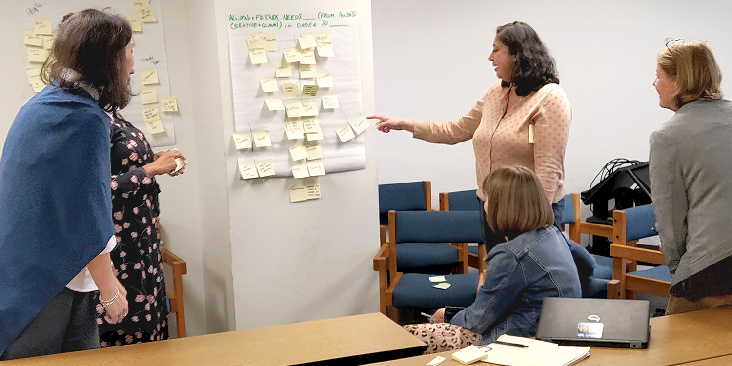 Four people in front of a board of post-its, brainstorming